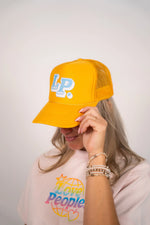 Person wearing a yellow cap with 'LP' logo and a pink shirt with 'Love People' text.
