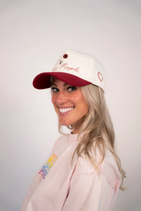Woman wearing a white and red cap with text on a plain background