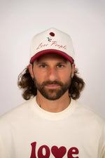 Person wearing a cap and t-shirt with 'Love People' text on a plain background