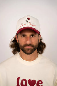 Person wearing a cap and t-shirt with 'Love People' text on a plain background