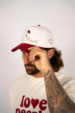 Person wearing a white cap with red text and a matching t-shirt on a plain background