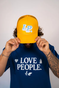Person wearing a blue 'LOVE PEOPLE' t-shirt and yellow cap with 'LP' logo.