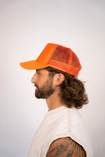 Man wearing an orange mesh cap on a white background