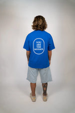 Person wearing a blue t-shirt with 'YOU ARE THE MESSAGE' text on the back, standing against a plain background.