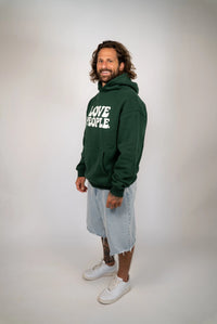 Man wearing a green hoodie with text, standing against a plain background