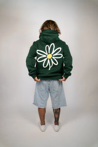 Person wearing a green hoodie with a white daisy design on the back against a plain background