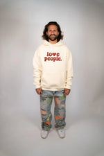 Person wearing a beige hoodie with 'love people' text on a plain background