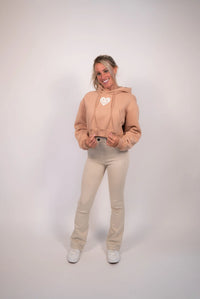Woman wearing a beige hoodie and pants on a white background